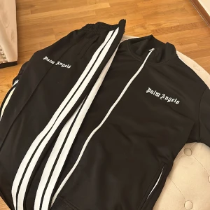 Palm Angels tracksuit - Knappast använd veligt ren inga problem utan bokstäverna på koftan vilket kan fixas med lim väldigt enkelt. Ny pris runt 4000kr för både koftan och byxorna