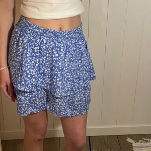 Blommig kjol - Supersöt kjol med små vita blommor. Brett resår i midjan som jag på bilen vikt in. Stora i storleken så skulle säga 38🤍