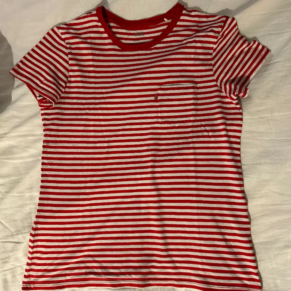 Röd/vitrandig t-shirt från Levi’s med ficka på bröstet. Bra skick och skönt material! Säljer då jag inte använder så mycket randigt längre. Produkten finns inte i sortimentet längre:). T-shirts.