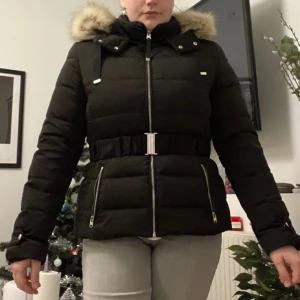Dunjacka med avtagbar pälsluva - Dunjacka med 100% genuin dun, fluffig insida på jacka och bälte med spänne runt midjan. Inköpt från Zara, nypris 1100kr. Vattenavvisande och väldigt varm då den är fluffig och fodrad på insidan. Storlek XL men liten i storleken, passar mer som M/L