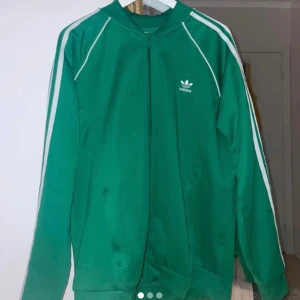 Grön adidas kofta  - (ps, mycket mer grönare i verkligheten, det är blixten som gör den oviss) En helt ny oanvänd adidas kofta. Köpt orginal från adidas egna hemsida. Super snygg och trendig och passar till ALLT!!!🌟