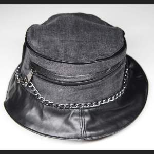 En bucket hat i mörk denim och konstläder med ficka och silver kedja runt. Jag har sytt den av återvunna tyg och material. Finns bara en exemplar i hela jorden :)