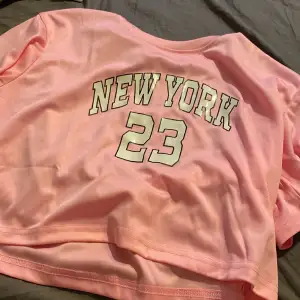 En fin Kroppad, rosa t-shirt med motivet NEW YORK 23. Aldrig använd då jag ej tyckte den passade på mig.