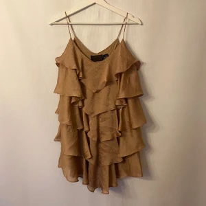 Volangtopp - En längre topp med volanger i en lite guldig/ beige färg. Märke: H&M. Storlek: S