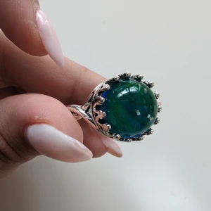 Retro Humörring med Värmekänslig Sten och Karvad Designkant - unika retro humörring, en fantastisk accessoar som kombinerar nostalgi med en modern twist.  Egenskaper:  Värmekänslig Sten: Stenens färg skiftar vackert mellan blått och grönt beroende på ljuset och din kroppstemperatur,. Storlek 10 ( motsvara 19.9 