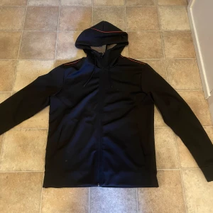 En hugo boss zip hoodie - En snygg hugo boss zip hoodie med röda detaljer och mönster på ryggen. Använt mycket men välvårdad, 8,5/10. Hör av dig vid frågor. Priset går att diskutera vid snabb affär!