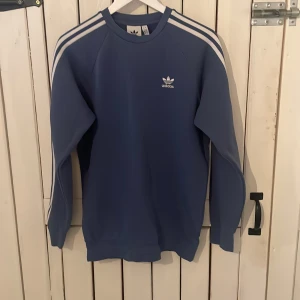 Adidas sweatshirt ljusblå  - En snygg långärmad tröja som är nästintill aldrig använd köpt i en butik i Stockholm för något år sedan för ca 500 så den har mestadels legat i en låda så den är så näst som ny 10/10 i storlek S 