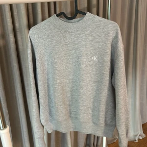 Collegetröja  - Grå collegetröja i kort modell från Calvin Klein jeans. Fint skick, hel och ren( inga fläckar) 
