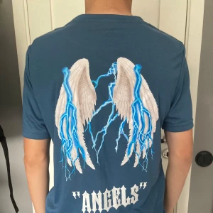 T-shirt med tryck på ryggen - En snygg blå t-shirt med ett nice tryck på ryggen. Tröjan är i ett jätteskönt material.