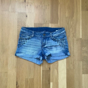 Snygga lågmidjade shorts - Jag säljer dessa snygga lågmidjade jeansshorts med nitar, eftersom de är för små. Shortsen är i jätte bra skick och har inga hål eller oavsiktliga slitningar! Midjemått är ca 37-38cm. Skriv gärna🥰 Storlek står inte men jag skulle säga storlek s!❤️❤️