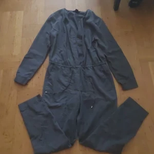 Grå tunn one piece - En bekväm och skön one set. Kan knäppas upp och har skjusterbara band. Andvänd 2 - 3 gånger. Har fickor