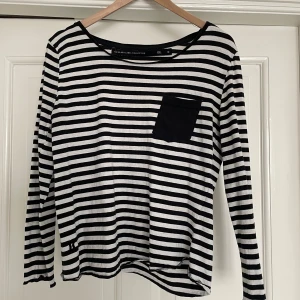 Fin svartvit randig tröja i storlek S - Fin randig tröja med knappdetalj på axeln. 100% bomull. Liten skavank vid lappen som inte syns vid användning, i övrigt mycket fint skick! Passar S-M 🌸