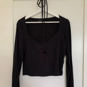 Svart tröja  - Jag säljer en svart tröja med ett snöre som man knyter runt halsen. Tröjan är i storlek L och är oanvänd i ett fint skick! 