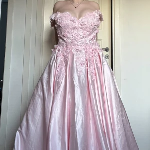 Ljus rosa balklänning  - Hej jag säljer min helt oanvända balklänning som har fina detaljer på överdelen och är en off sholder klänning men går att dra över på axlarna.  Kontakta via intresse eller tryck på köp nu