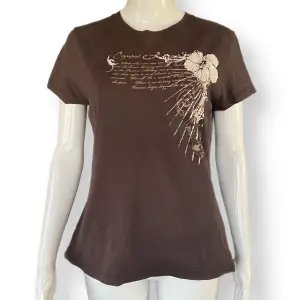 En mörkbrun t-shirt med hibiskusprint, i fint skick. Storlek M, från Sun T’s. 100% bomull. MÅTT: Axel till axel 39cm, ärmlängd 15.5cm, armhåla till armhåla 48cm & längd 62cm 