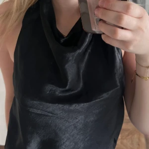 HM TOPP - Säljer denna super snygga svarta halterneck topp i satin med öppen rygg från HM. Den är i storlek S och har aldrig används därav säljes☺️
