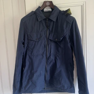 Stone island overshirt  - Säljer min stone island neslan overshirt som köptes på Nk för ett par år sedan. Varan är sparsamt använd och i gott skicka, dock ett mindre hål vid bröstfickan ( ej synligt vid användning) Nypris: 4000, mitt pris: 800 strl: S fits M
