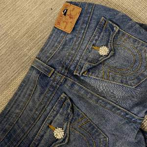 Galet snygga true religion jeans som tyvärr är för stora för mig🥲ganska använda men det enda som märks är lite på true religion lappen (syns på förstabilden)och att någon liten pärla på knappen fram har åkt av. Verkligen så fina!!Lowwaist & bootcut💕