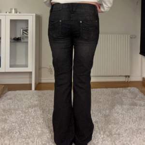 Svarta lågmidjade jeans. Midjemått 82 cm. Innerbenslängd 84 cm.