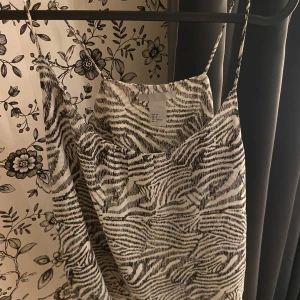 Zebramönstrad klänning - Säljer ett snyggt zebramönstrat linne med smala axelband. Är perfekt för sommaren och har en lös passform som gör den bekväm att bära. Materialet känns mjukt och skönt mot huden.