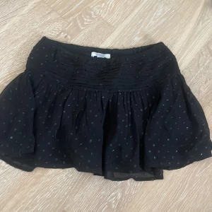 Svart kortkjol från Gina Tricot - Säljer en superfin svart minikjol från Gina Tricot. Kjolen har ett sött prickigt glittrigt  mönster och en bred midja som ger en bekväm passform. Perfekt för både vardag och fest! 💗