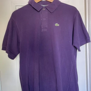 Lacoste piké  - Lila Lacoste piké i storlek M. I fint skick!