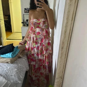 Fest klänning  - En snygg blommig klänning som kan användas på både fester, bal mm Den är i bra skick och kommer med ett spaghetti straps som man kan sätta till om man vill 