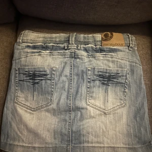 Jeans kjol  - Jag säljer denna jeans kjol med dekorerade bakfickor eftersom att den inte kommer till användning längre, den är i väldigt bra skick men använd några gånger. Inuti är det lite mjukis material. 