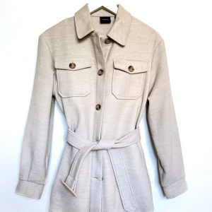 Beige skjortjacka - Beige jacka. Passar för sensommar/höst. Kan användas med eller utan skärp i midjan. Aldrig använd, lappen är kvar. I storlek S. Från Vero Moda. Org. pris 650 kr.