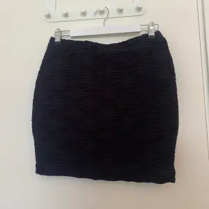 En kort svart kjol med mönster i storlek 40