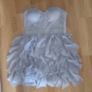 Cocktail klänning  - Fin klänning från Bik Bok i kall grå färg med lite lila nyans. Volanger vid kjolen och inbyggd bh med gummi så den inte åker ner. Dragkedja med spänne och stretchig i ryggen. I bra skick🦋