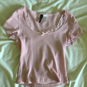 Baby rosa t shirt med en rosett🎀 - En gullig rosa tröja ifrån hm divided. Tröjan är i storlek xs och är bara testad men aldrig använd. Säljer pågrund av att den inte helt sitter mig i smaken. Köpt för kanske 230 eller något sådant.