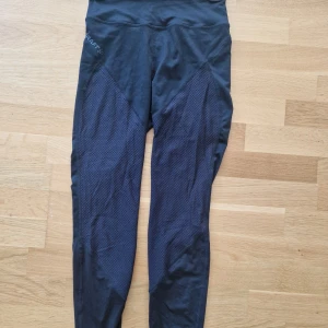 Craft Träningstights  - Storlek: S  Material: 92% Polyester, 8% Elastan.  Använda en gång. Luftiga med ihåligt tyg vid knän och vader.  Inte överdrivet tighta så passar en medium. 