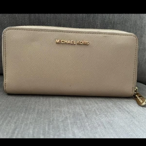 Michael kors plånbok  - Säljer min beiga Michael Kors plånbok med guld detaljer. Använd men fortfarande i fint skick! 