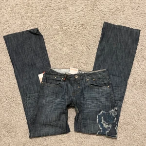 Lågmidjade jeans  - As snygga lågmidjade bootcut jeans med coola detaljer!!🪩 Midjemått rakt över: 35cm.  Innebenslängd: 82cm.  Benbredd: 23cm. Har tyvärr inga bilder med dem på!