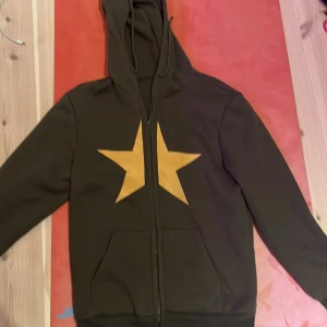 Stjärn hoodie - En hoodie med en stjärna i mitten! Den funkar bra och är varm av sig, använd några få gånger men inte mycket.