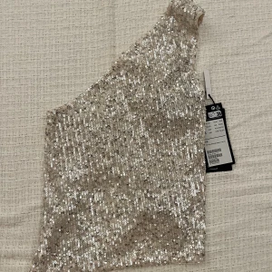Glittrig topp - Glittrig topp men bar rygg och knytdetalj från Weekday. Storlek XS. Oanvänd med prislappen kvar. 