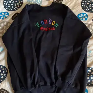 Skön långärmad tröja med ”London England” skrivet i färglad gotisk text