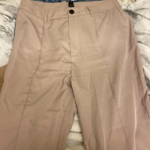 Beiga kostymbyxor  - Lite tunnare material på dessa kostymbyxorna. Man kan ha dem på sommaren de är ganska luftiga och sköna. Färgen är lite ljusare än vad det ser ut o vara på bilden. Byxorna används ej drf säljer jag dem