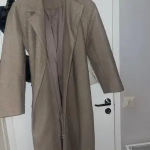 En brun/beige lång kappa. Knappt använd därav säljes. Den är köpt från Ginatricot och är i storlek M