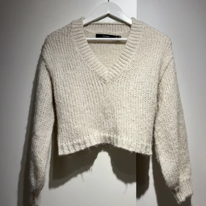 Stickad tröja - En vit/begie stickad tröja. Genom v-ringningen så går det att snyggt ha den lite off shoulder. Eller perfekt över klänningar. Eller varför inte till jeans? Ja den funkar till allt. 