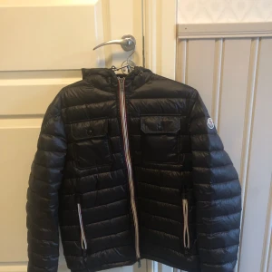 Moncler Jacka Svart - Säljer nu min snygga moncler jacka som är i super bra skick (9/10) 🍾🍾Storleken är 2 vilket motsvarar S/M 🔥 Har inge bevis på att den är äkta då jag köpte jackan från Plick. Har du frågor eller prisförslag är det bara att höra av sig! 🙌