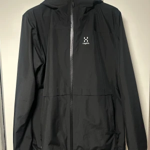 Haglöfs Skaljacka GTX Goretex - Tillverkat av tvålagers återvunnet GORE-TEX-tyg för hållbart skydd mot väder och vind PFAS-fria DWR-behandlade vatten- och smutsavvisande ytor Två framfickor med blixtlås och en innerficka med blixtlås Elastisk huva Elastiska ärmslut 