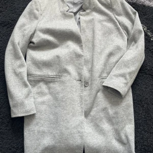 Ljusgrå Kappa - Ljusgrå kappa från Vero Moda i strl 40. Nästan helt oanvänd. Säljs för den inte används längre. 