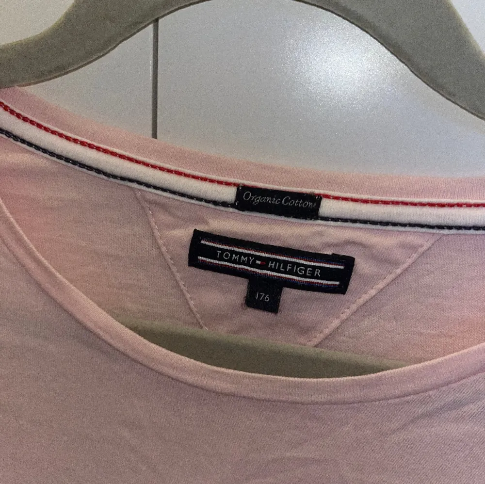 Tommy Hilfiger t-shirt i ljusrosa med ett blått tryck fram. Endast använd några enstaka gånger. Storlek 176 men passar en Xs.🩷. T-shirts.