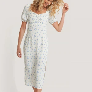 Blommig midiklänning - Såå fin blommig midiklänning från NA-KD🌸 I storlek 38. Den har en slits på ena sidan och försluts med en dragkedja i sidan. Säljer då den tyvärr inte passar mig längre. 