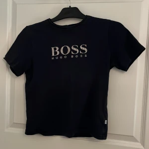 Blå Hugo boss t-shirt  - Säljer min Hugo boss t-shirt. Bra skick. Säljer pga att den är  för liten. Den ser svart ut på bilden men den är blå. 
