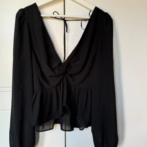 Svart blus H&M - Helt ny, prislapp kvar. Storlek M. Djup urringning samt öppen rygg. Cropped.  Har knytband i ryggen. 