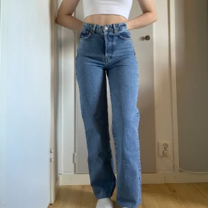 Blå jeans - Blå högmidjade jeans från Bikbok. Knappgylf, raka vida ben. Varsamt använda. Dessa har en liten fläck på ena byxbenet (inget som är super synligt) därav priset🦋Jeansen är uppsydda i benen. Midja-65,5 cm Längd- 88,5 cm Innerben- 65 cm