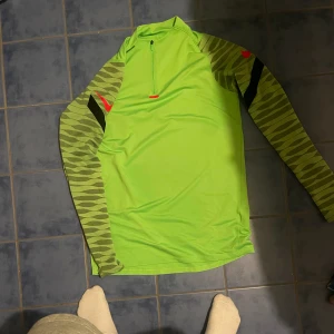 Nike tränings tröja! - Denna Nike tränings tröja är i en fin neon grön färg med rosa detaljer! Den är knappt använd, ca 2-3 gånger. Säljer pga för stor. I storlek M! Den sitter tajt mot kroppen, bibehållet värme ordentligt. Perfekt till dig som gillar att träna!! Kp förmer